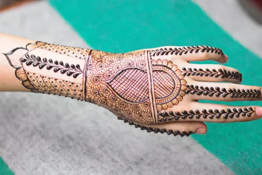 Close up of a hand adorned with a detailed meh - arabic mehndi
