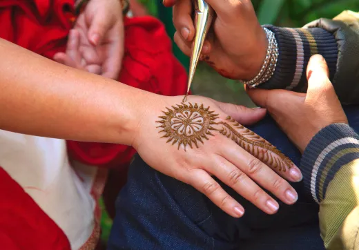 Woman getting an intricate henna design applie - henna hair colour