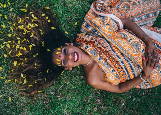 Smiling woman in a colorful sari lying on gras - henna hair
