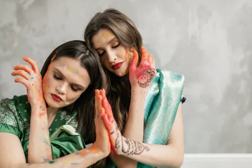Two women enjoy the holi festival adorned in t - henna paste
