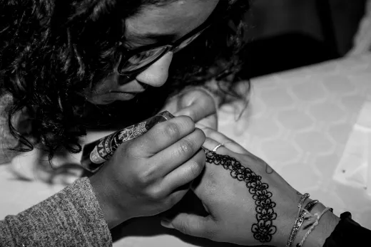 Close up of woman applying intricate henna tat - henna on skin