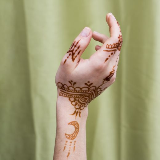 Woman hand with mehndi paints near textile - simple Arabic mehndi design